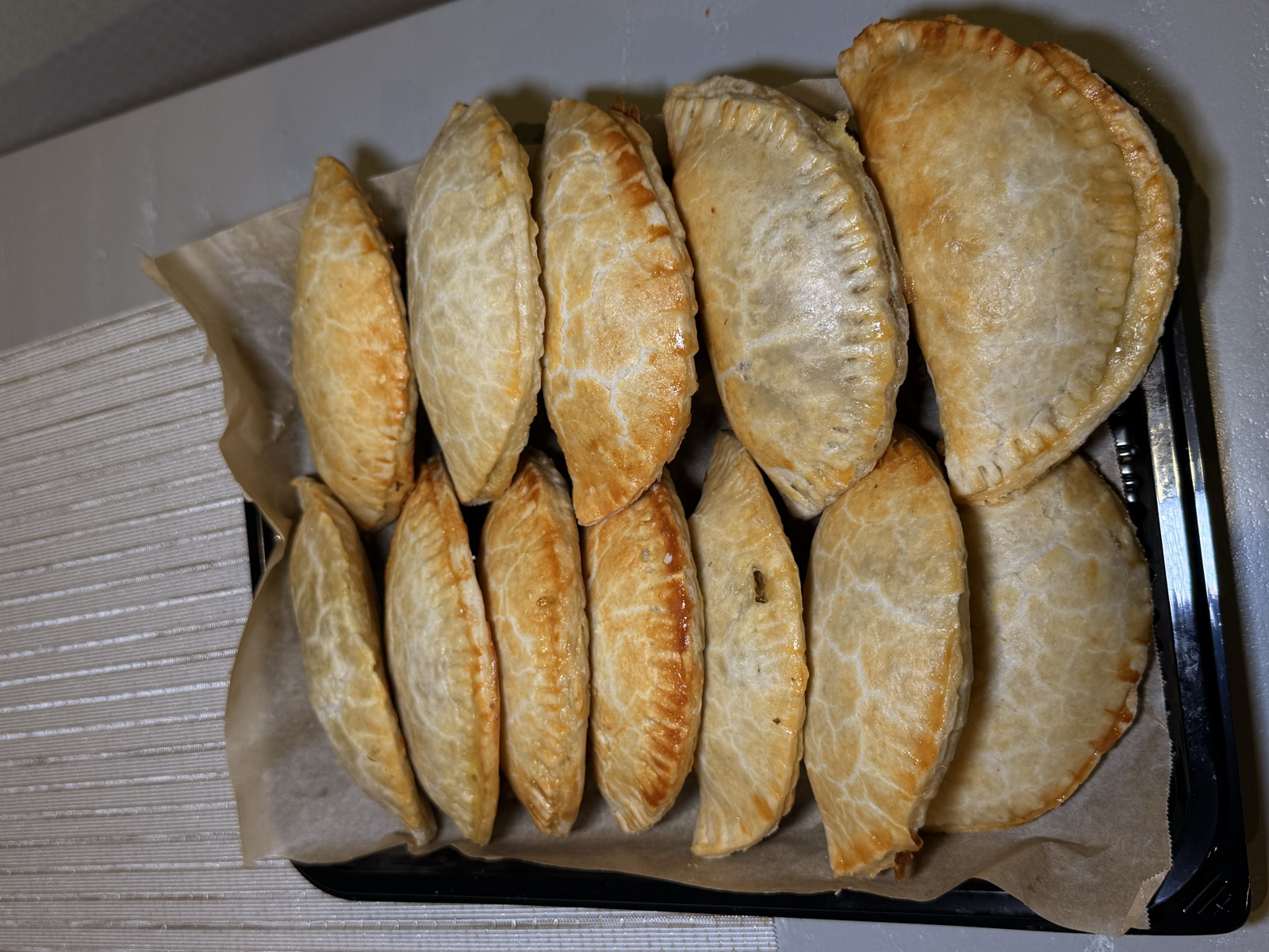 A parchment-lined tray of freshly baked golden meat pies