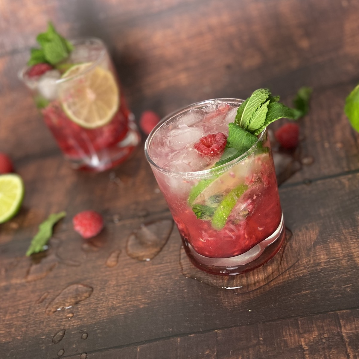 A freshly poured mocktail over ice with lime, mint and raspberries